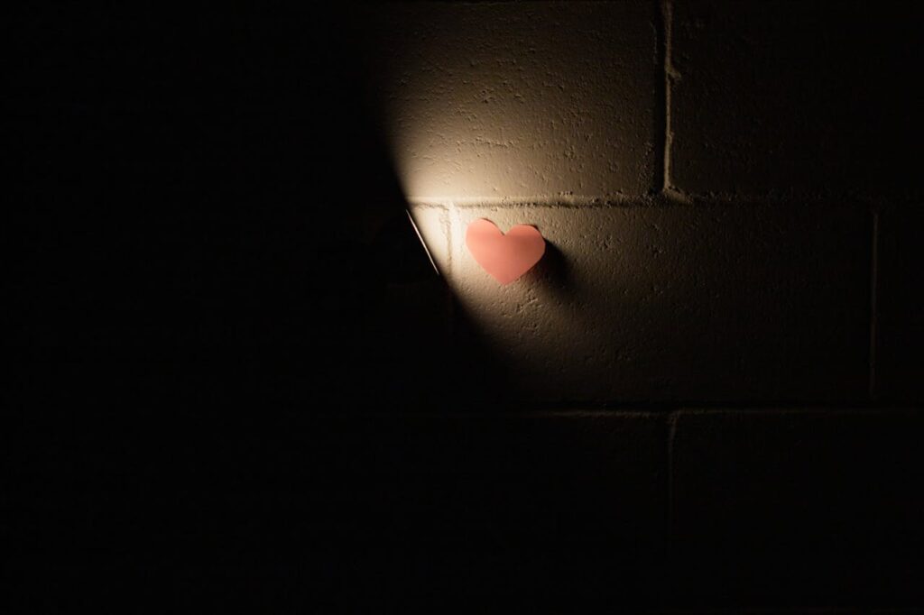 pexels photo 7453098 A heart-shaped sticky note illuminated by spotlight on a dark wall creates a vivid contrast.